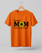 Mom quote graphic half sleeve t-shirt featuring “Being a MOM makes my life complete” with sunflower design