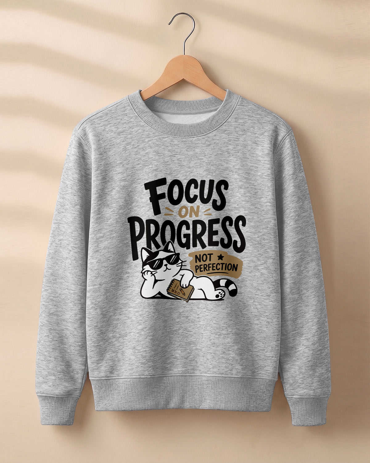 Motivational graphic sweatshirt featuring relaxed cat wearing sunglasses artwork with Focus on Progress, Not Perfection quote printed on cotton fabric