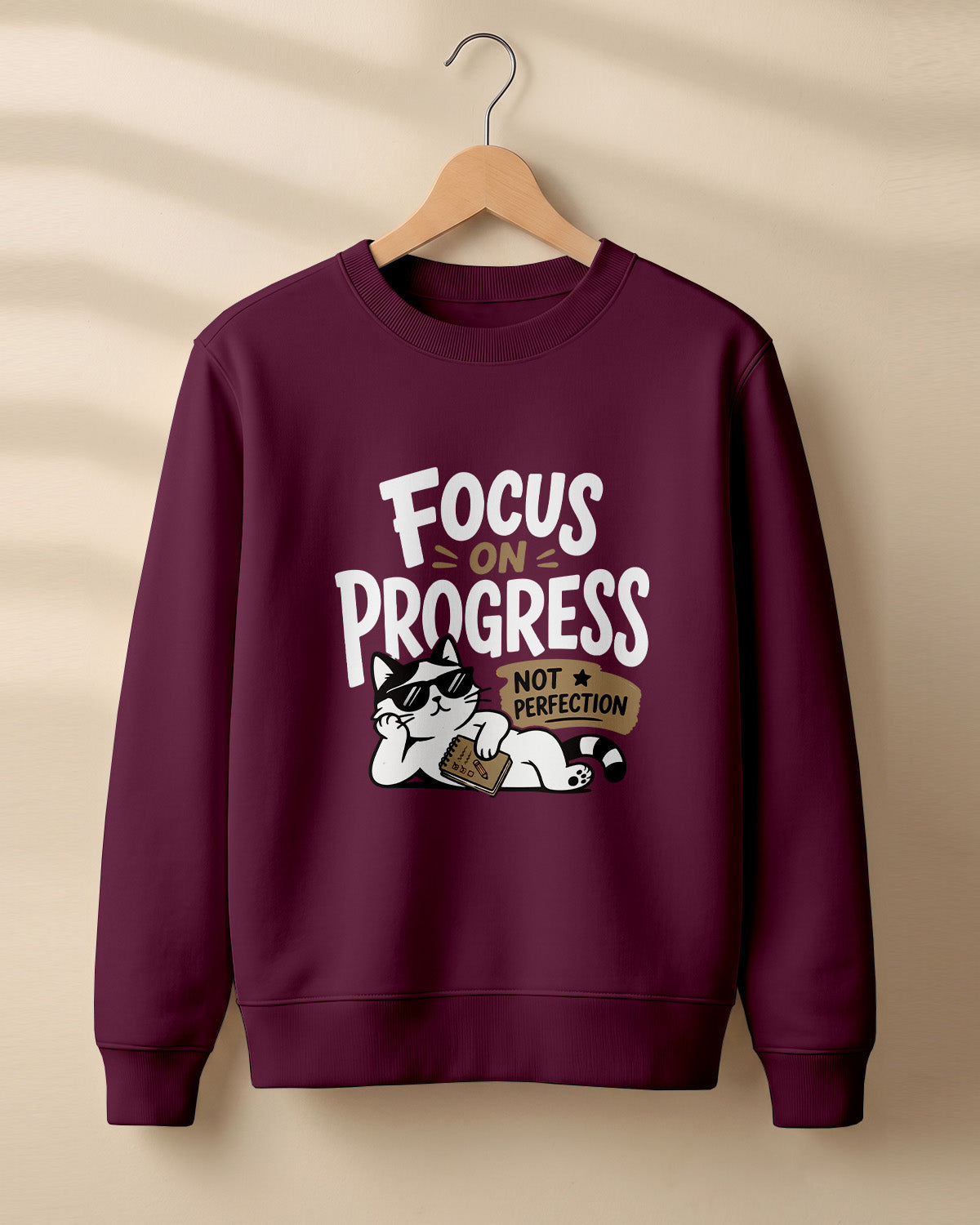 Motivational graphic sweatshirt featuring relaxed cat wearing sunglasses artwork with Focus on Progress, Not Perfection quote printed on cotton fabric