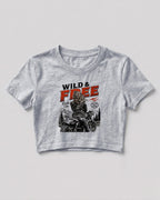 Xenovaurban crop top featuring a woman riding a motorcycle against a scenic mountain backdrop with Wild & Free typography