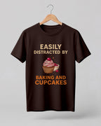 Foodie graphic half sleeve t-shirt featuring “Easily Distracted by Baking and Cupcakes” typography with colorful cupcake illustration printed on premium cotton fabric.