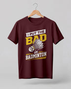 Humorous sports graphic half sleeve t-shirt featuring “I Put the Bad in Badminton” typography with shuttlecock illustration printed on premium cotton fabric.