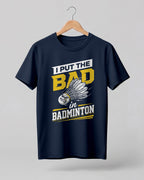 Humorous sports graphic half sleeve t-shirt featuring “I Put the Bad in Badminton” typography with shuttlecock illustration printed on premium cotton fabric.